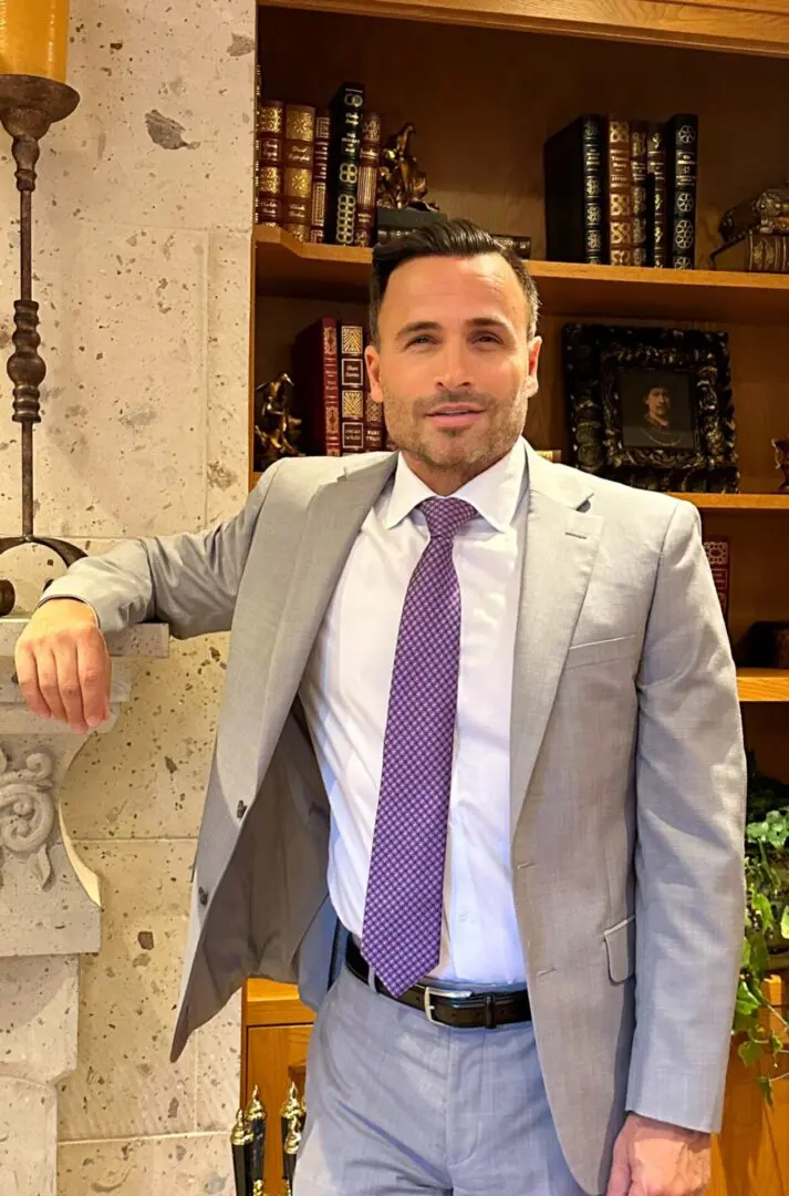 A man in a suit and tie leaning on a wall.