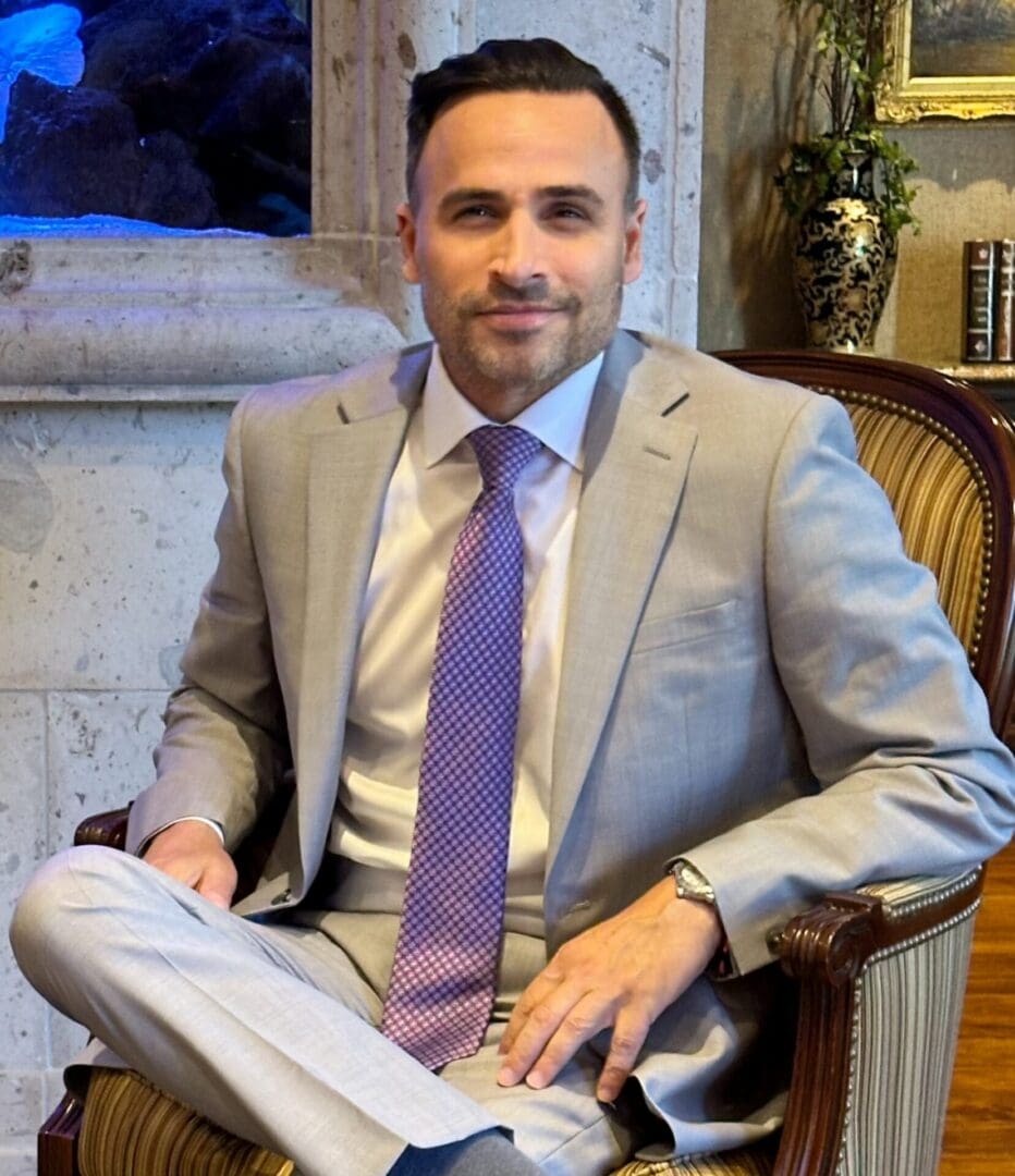 A man in suit and tie sitting on chair.