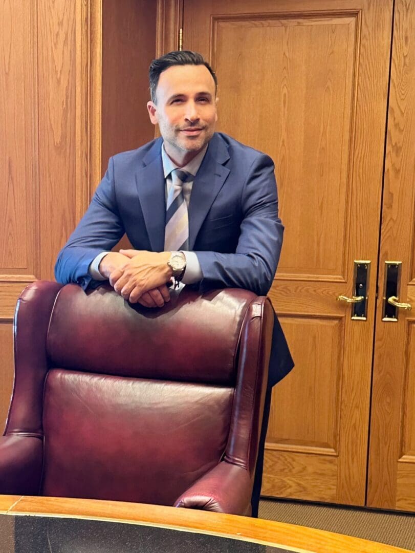 A man in a suit and tie sitting on top of a chair.